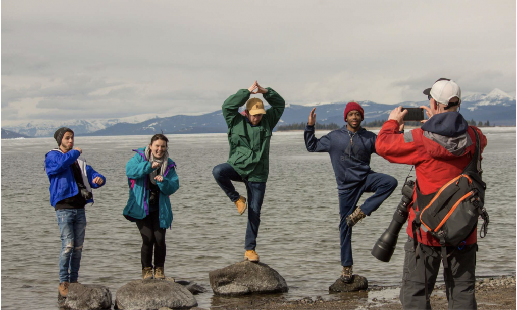 Man taking picture of students on rocks posing